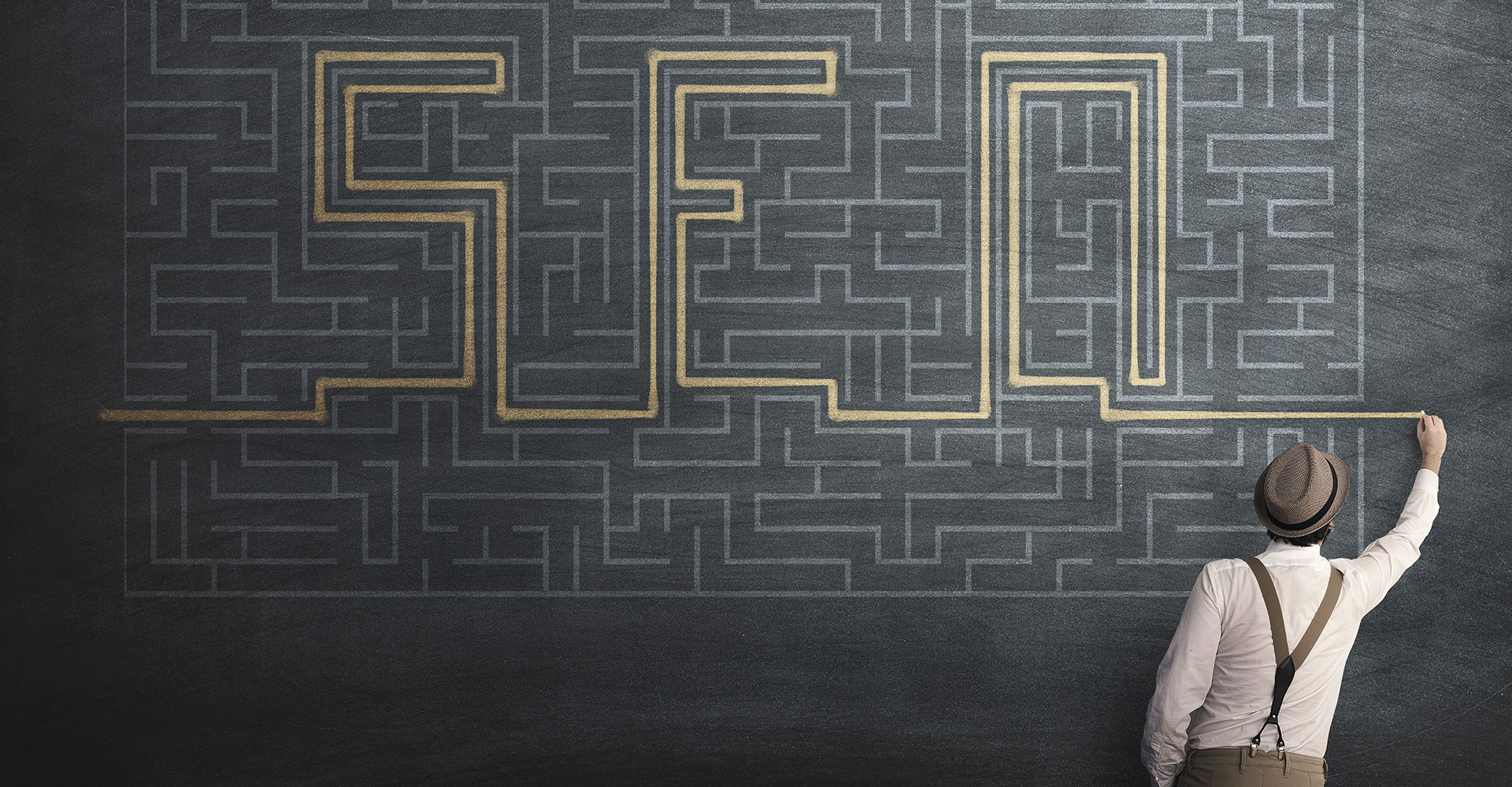 Photo of a man drawing the letters SEO through a maze on a chalkboard