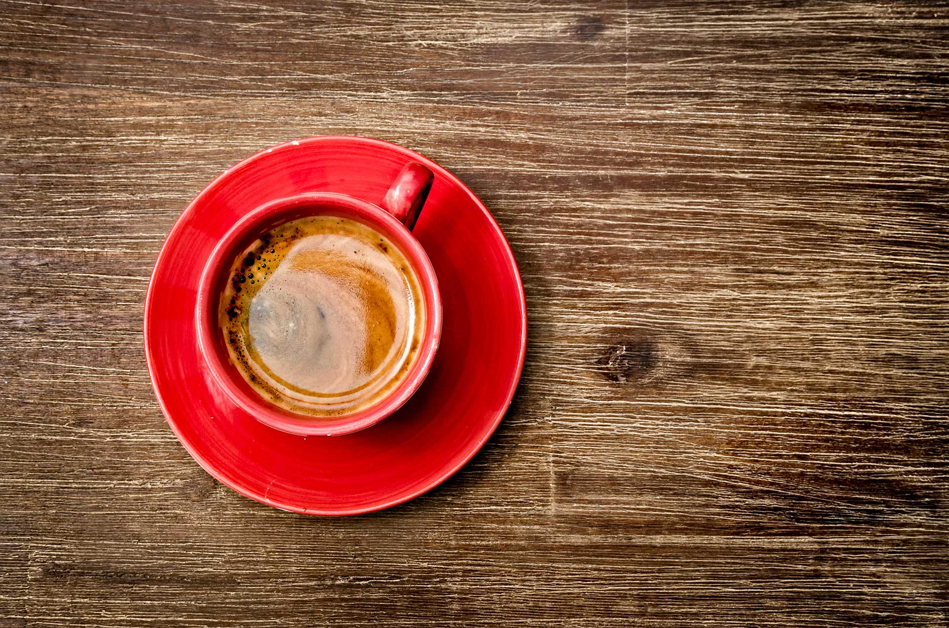 Photo of a cup of coffee on a wood tabel shot from above