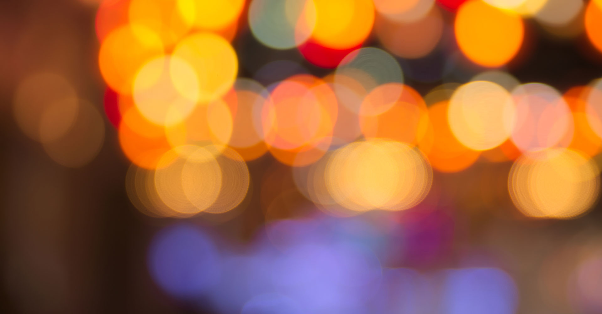 Photo of lights blurred in yellows, oranges, and blues.