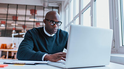 Photo of a man in an office working with a laptop. 