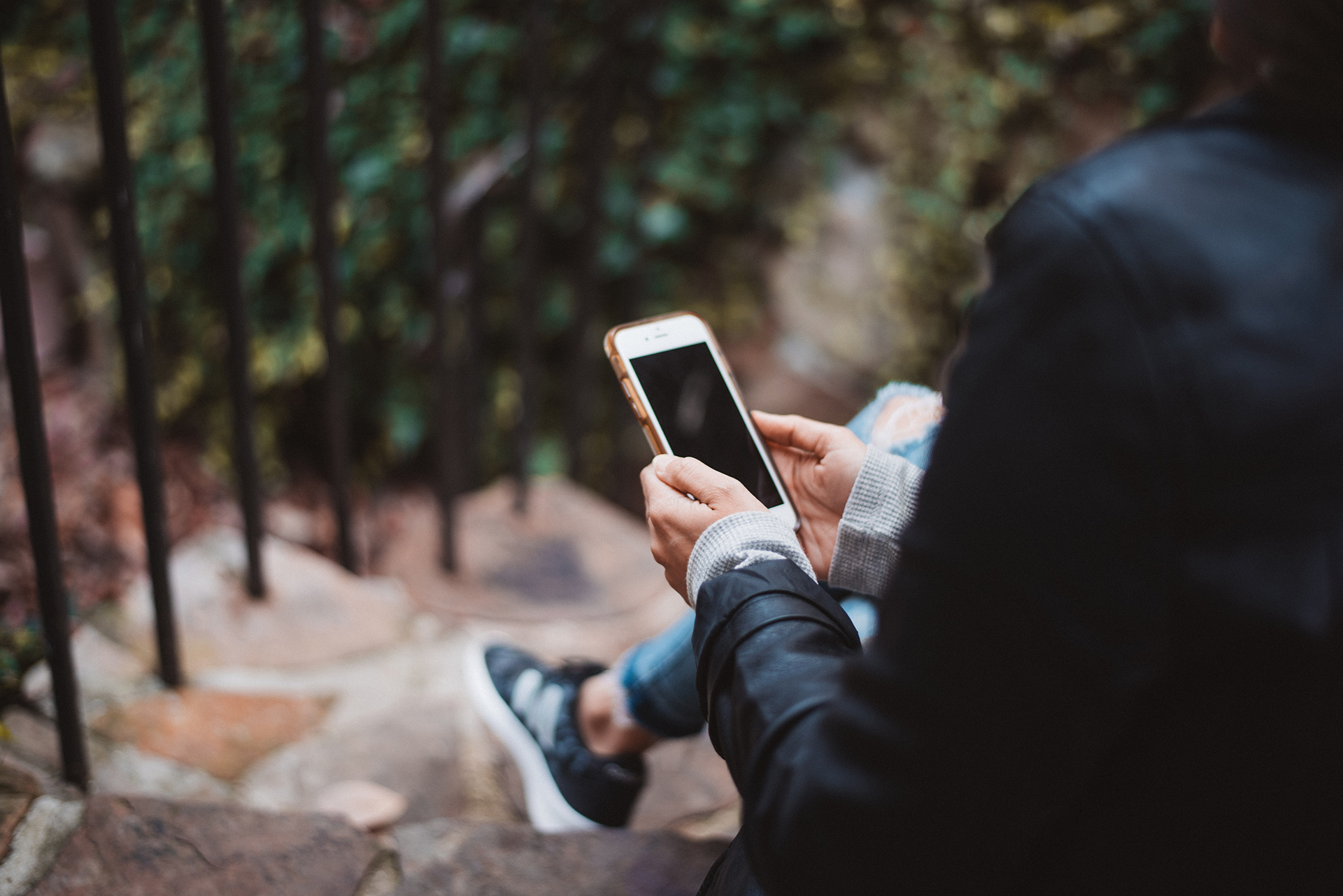 Photo of a person in the park looking at their cell phone