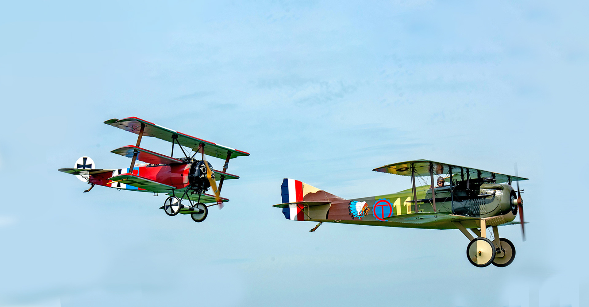 Profile photo of two World War I biplanes in flight, in motion from left to right. 